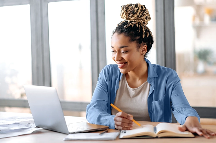 imagem de uma jovem, sentada em uma mesa, em frente a um notebook, realizando terapia online